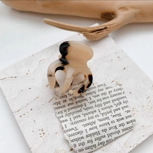 Close-up of tortoise shell mini hair claw clip on vintage book page with artistic shadows