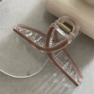 Detailed close-up of a minimalist clear acrylic hair claw clip with brown inlay detail
