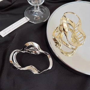Detail showing irregular wavy gold and silver metal hair claws on black silk background