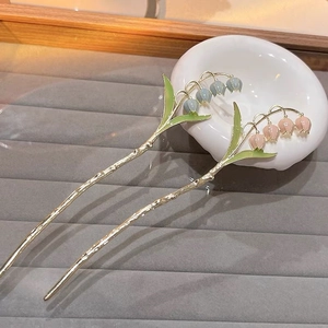 Gros plan sur d'élégantes épingles à cheveux muguet avec fleurs en émail bleu et rose