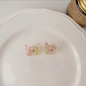 Detail of small butterfly hair clips with pink and green gradient marble texture on a tray