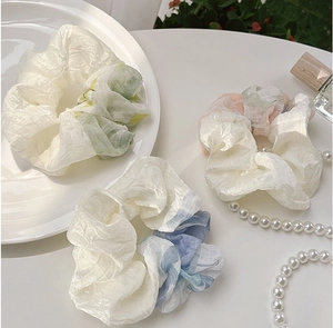 Detail of oversized pleated scrunchies with white texture and colorful plaid patterns
