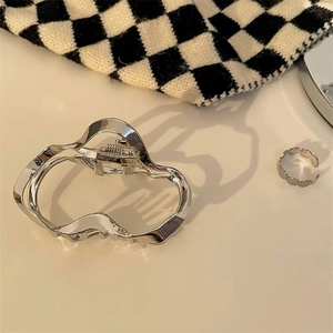 Detail of silver wavy metal hair claw clip and matching ring on checkered fabric