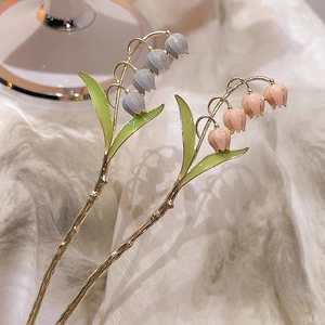 Détail des épingles à cheveux muguet rose et bleu avec une finition dorée élégante