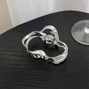 Detailed view of silver metallic shark hair clip with irregular hollow geometric design