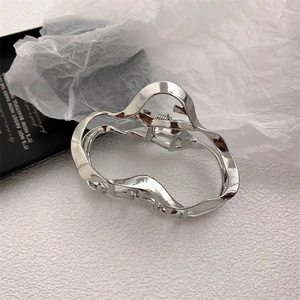Macro detail of irregular silver geometric metal hair claw clip with wave design