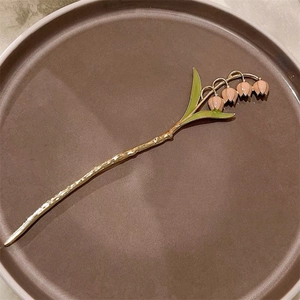Détail d'épingle à cheveux muguet doré avec fleurs en émail rose et feuilles vertes