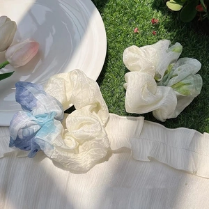 Pastel plaid oversized mesh scrunchies in blue and green on a grassy summer background