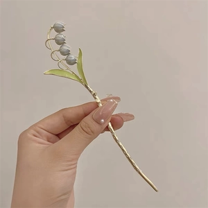 Détail du pic à cheveux muguet élégant avec métal doré et fleurs en émail bleues