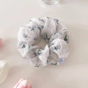 Gros plan d'un chouchou floral blanc et bleu avec texture à carreaux sur fond minimaliste