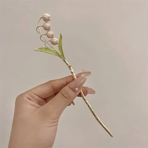 Détail de l'épingle à cheveux muguet élégante avec pétales roses et feuilles vertes