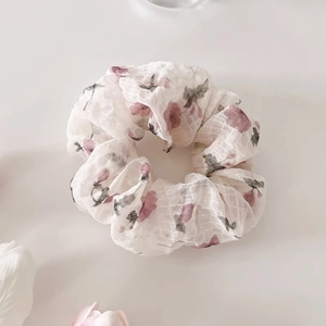 Détail du chouchou fleuri beige avec texture à carreaux et motifs de fleurs violettes