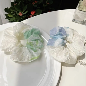 Detail of color-block mesh scrunchies with plaid patterns on a white porcelain plate