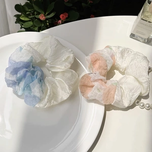 Detail of light blue and orange mesh scrunchies with sheer plaid texture on a ceramic plate