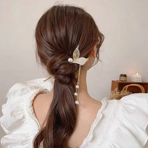 Detail of mermaid tail hair pin with pearl tassels styled in a low ponytail