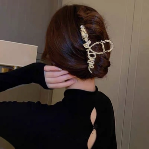 Close-up of golden metal hair claw with rose flower design and Love letter engraving