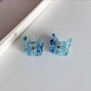 Detail of blue marble butterfly hair clips with metal spring mechanism on white desk