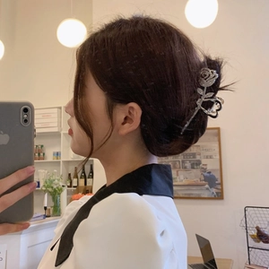 Close-up of a silver rose metal hair claw clip with rhinestones worn on a bun hairstyle