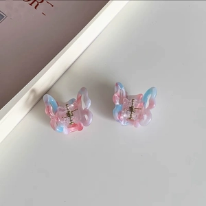 Close-up of small butterfly hair claws in gradient pink and blue marble resin finish