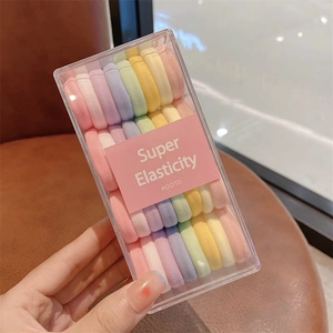 Détail d'un ensemble d'élastiques à cheveux macaron colorés dans une boîte transparente
