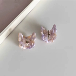 Detail view of two small butterfly hair clips with purple and white marble patterns