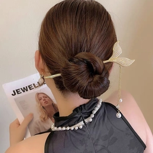 Close-up of mermaid tail hair pin with sparkling rhinestones and pearl tassels on hair