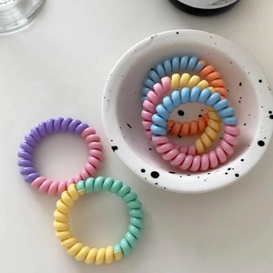 Vue détaillée d'élastiques à cheveux spirales macaron dans un bol en céramique