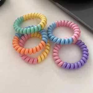 Gros plan de quatre élastiques à cheveux spirales aux couleurs pastel macaron mélangées