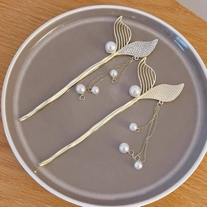 Close-up of golden mermaid tail hairpins with pearl tassels and sparkling rhinestones