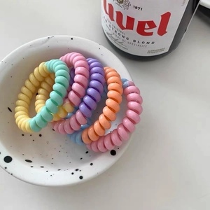 Gros plan d'élastiques à cheveux en spirale de couleur pastel dans un bol déco