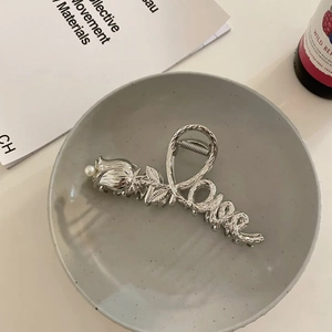 Detailed silver metal hair claw with rose design, pearl accent, and Love engraving
