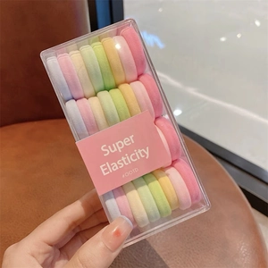 Vue macro d'élastiques à cheveux colorés en boîte transparente avec étui rose