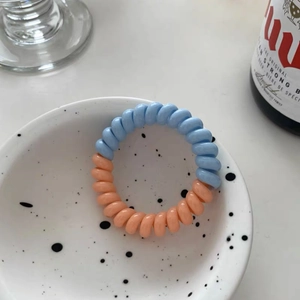 Vue détaillée d'un élastique spirale bicolore bleu et rose dans un bol en céramique