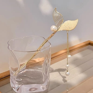 Detail of mermaid tail hair stick with delicate pearls and elegant gold tassels