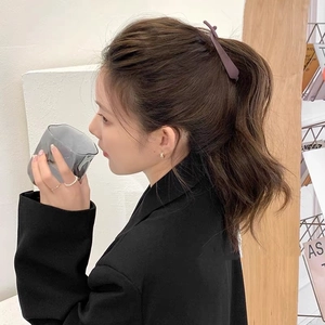 Détail d'une pince banane violette mate sur queue de cheval avec un blazer noir chic