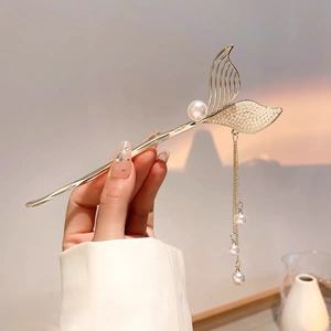 Detailed view of mermaid tail hair pin with hanging pearls and elegant gold tassels