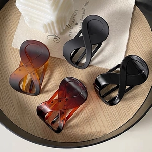 Close-up of four assorted 8-shaped hair claws in matte black and tortoiseshell finishes