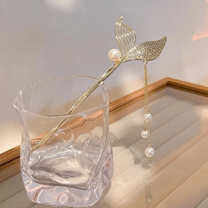 Detail of golden mermaid tail hair stick with shimmering crystals and pearl tassels