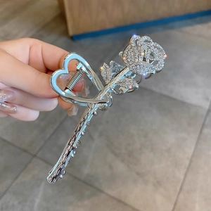 Detail of silver metal hair claw with hollow heart handle and rhinestone rose design