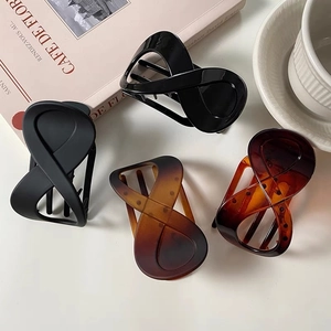 Set of four infinity-shaped hair claws in matte black, gloss, and tortoise shell patterns