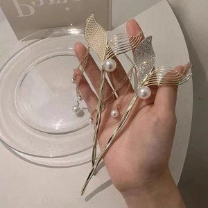 Close-up of golden mermaid tail hairpins with elegant pearls and sparkling tassels