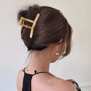 Detail of a large cream marbled acetate hair claw clip worn on a model's head
