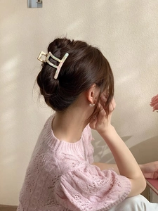 Detail of elegant marble texture acetate hair claw clip worn on a woman's bun hairstyle