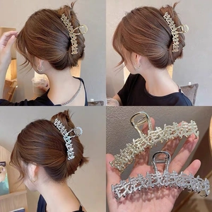 Dettaglio dei fermagli per capelli in metallo oro e argento con motivi di caratteri cinesi
