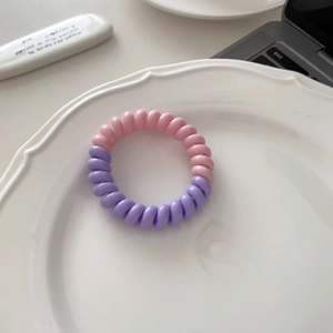 Détail d'un élastique spirale rose et violet sur une assiette blanche au style épuré