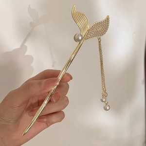 Detail of golden mermaid tail hair stick with pearls and long tassel pendant