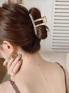 Close-up of a large marble texture acetate hair claw clip worn on a woman's ponytail