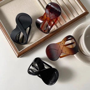 Detail showing matte black and tortoiseshell claw clips with infinity cross design