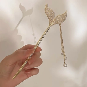 Detail of golden mermaid tail hair pin with pearl tassels and crystal inlays