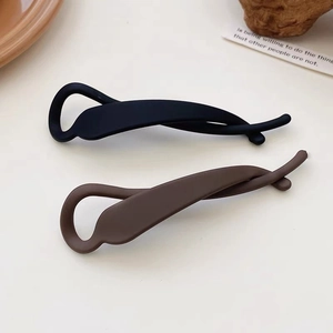 Barrettes banane en résine mate noire et marron présentées avec des accessoires